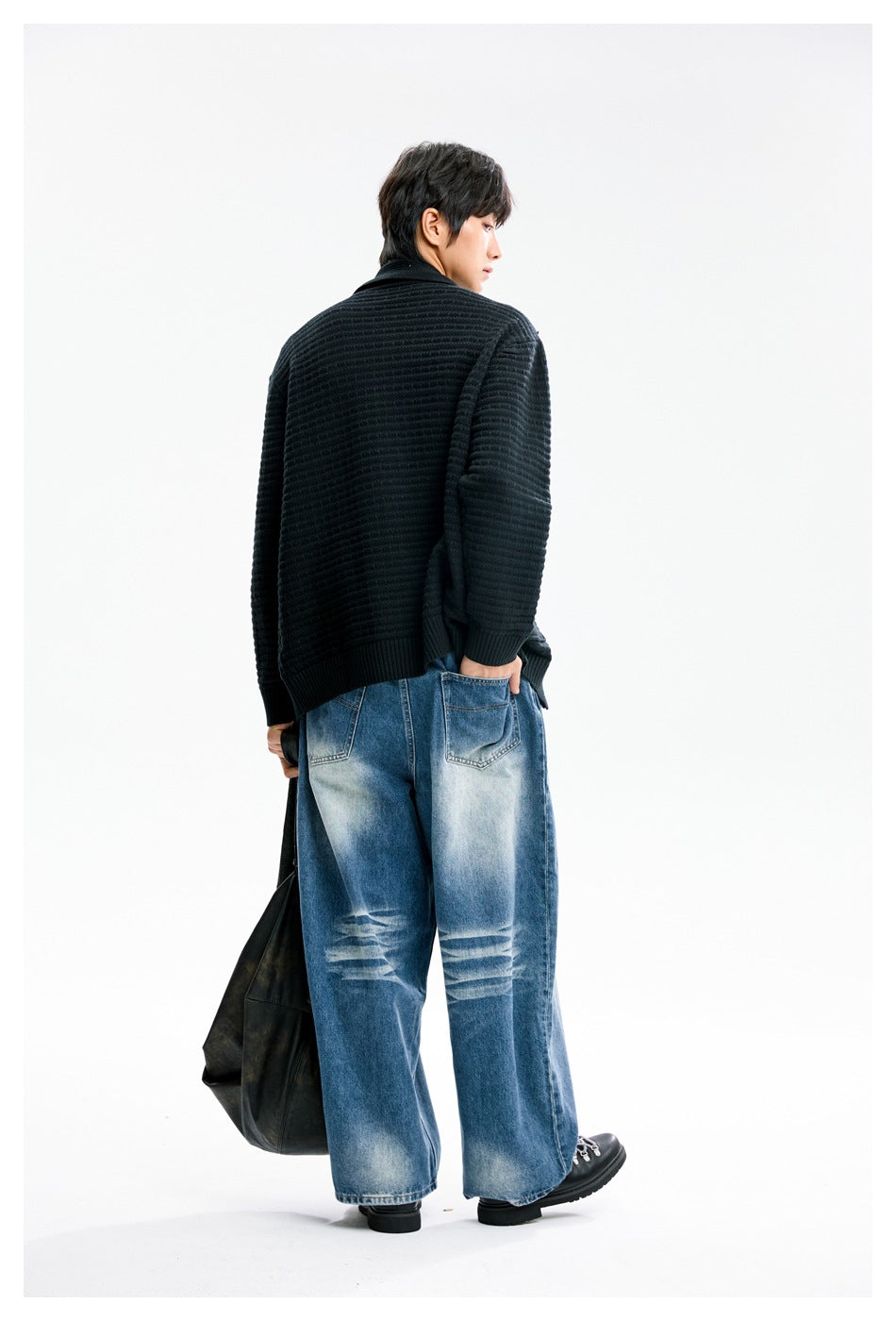 Back view of a model wearing a black textured knit jacket with ribbed cuffs and hem.