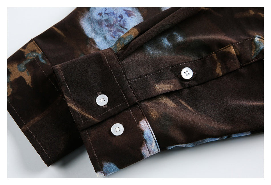 Close-up of a printed dark brown shirt cuff with three white buttons and visible stitching.