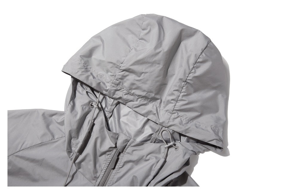 Close-up of a light gray jacket hood with adjustable drawcords and part of the front zipper.