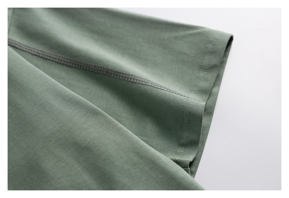 Close-up of a sage-green sleeve hem with visible stitching and overlock seams.