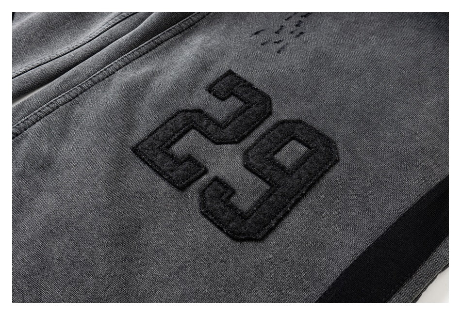 Close-up of a raised black “29” appliqué on charcoal gray fabric.