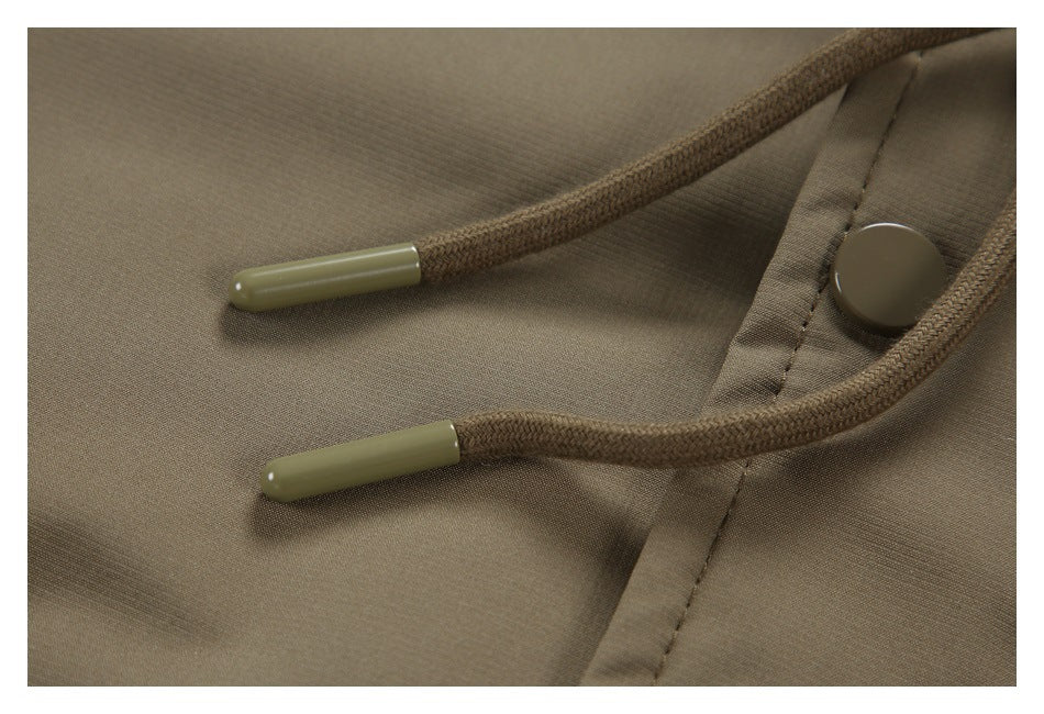 Close-up of brown jacket drawcords with olive-colored tips beside a snap button.
