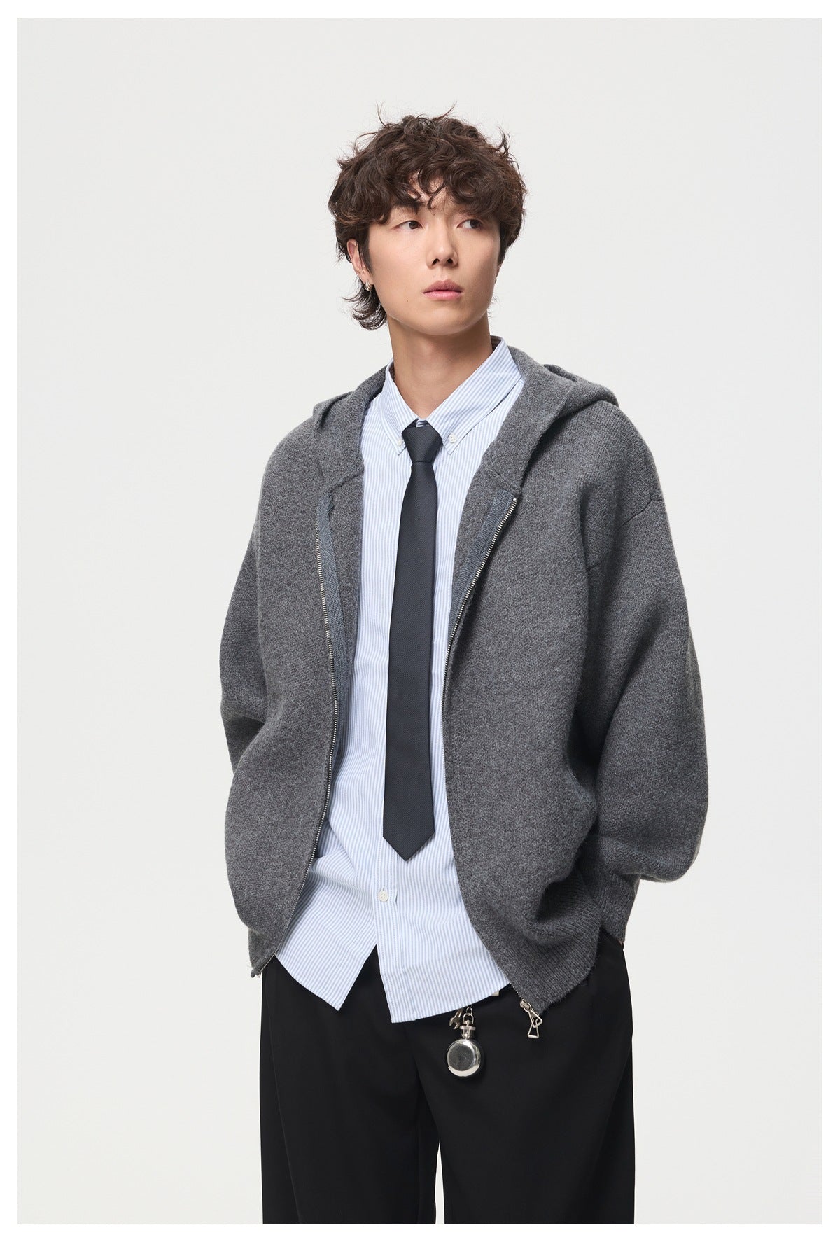 Front view of a model wearing an open charcoal-gray hooded cardigan over a striped shirt and dark tie.