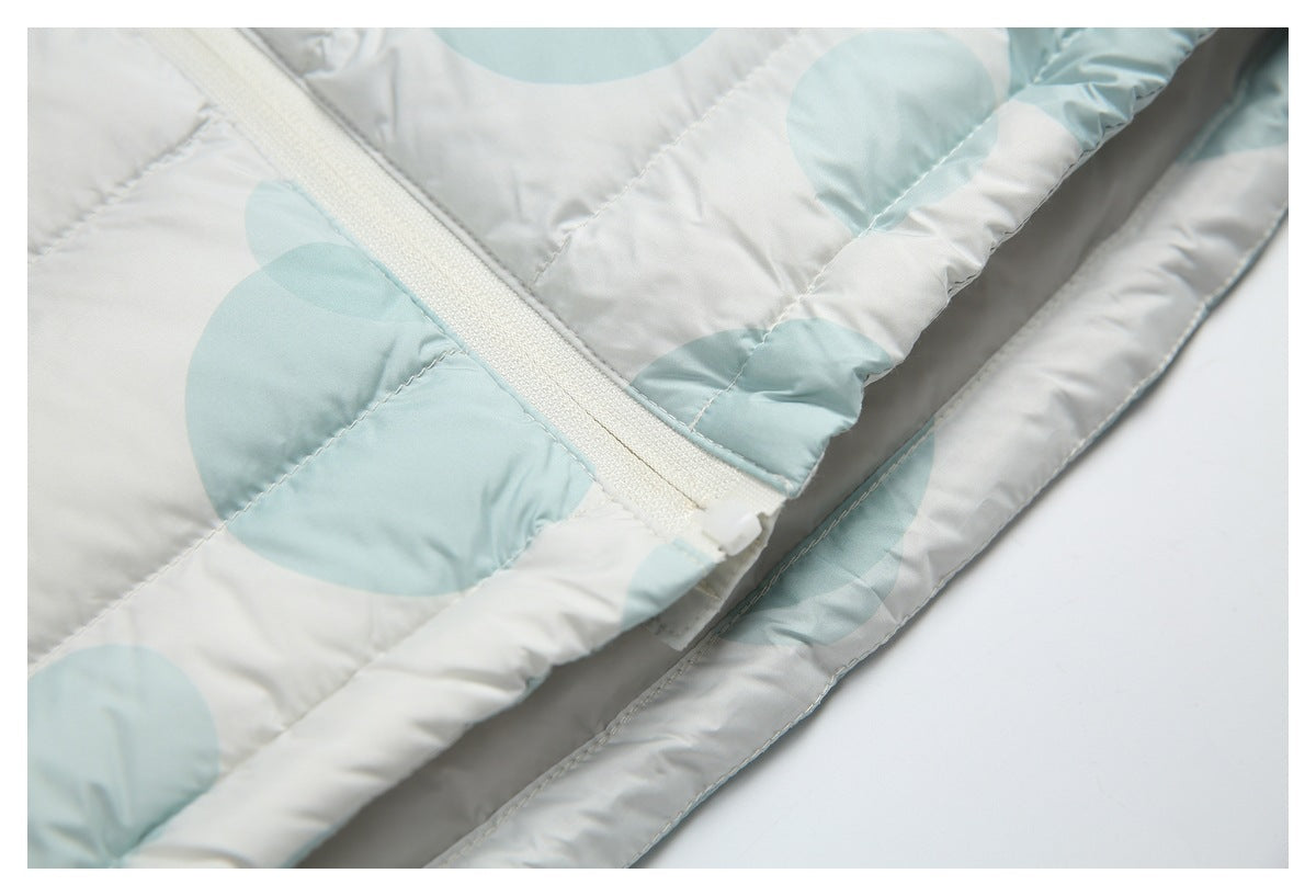 Close-up of the white front zipper and overlapping hem on a pale aqua circle-print puffer jacket.