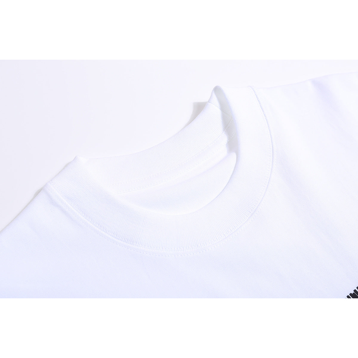 Close-up of a white T-shirt's ribbed crew neckline, with a small black graphic partly visible at the edge.