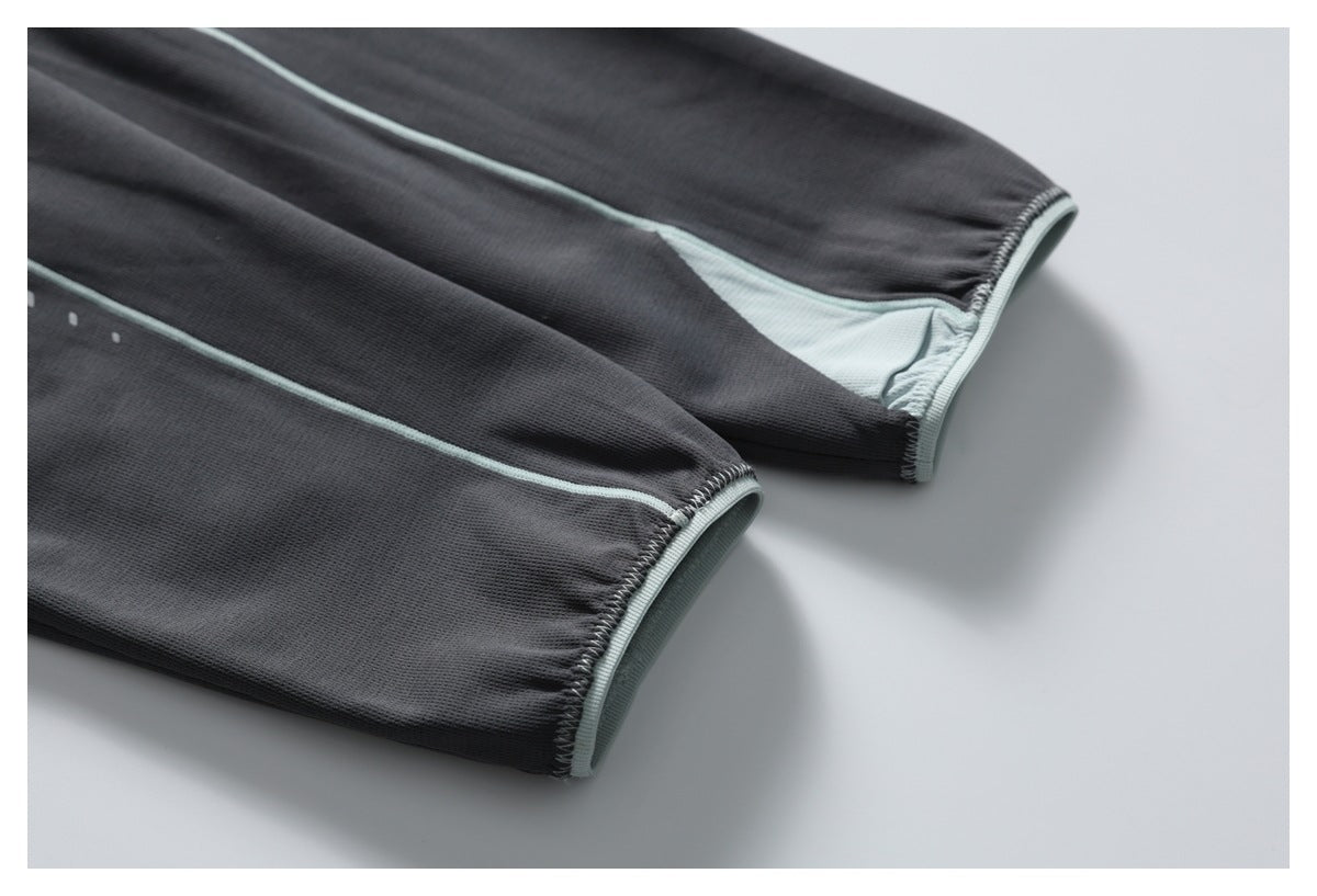 Close-up of two charcoal garment cuffs with pale mint edging and inner panels.
