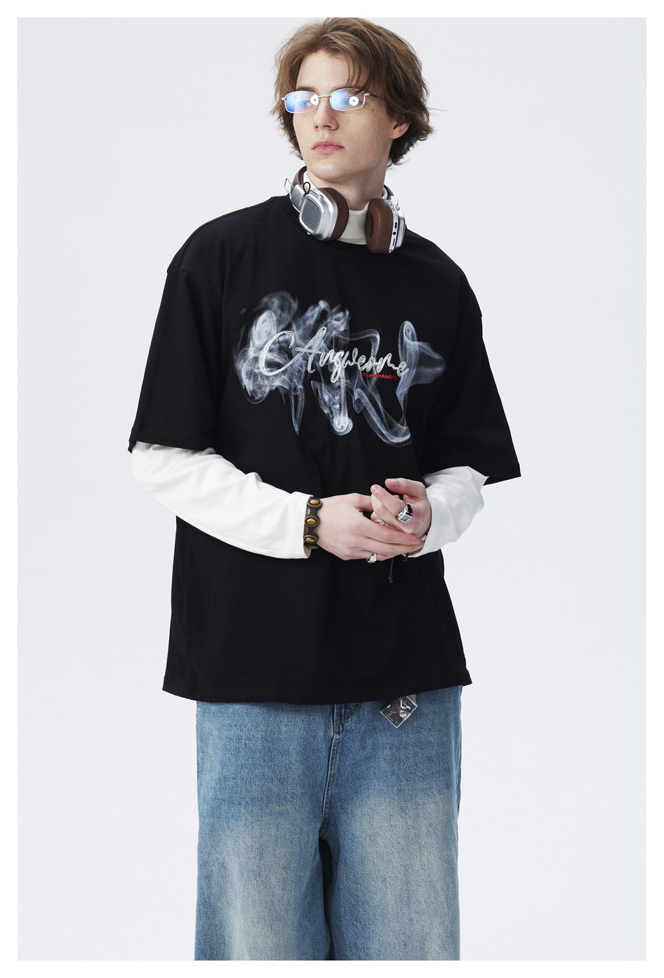 Model wearing an oversized black T-shirt with a smoky script graphic over a white long-sleeve shirt.