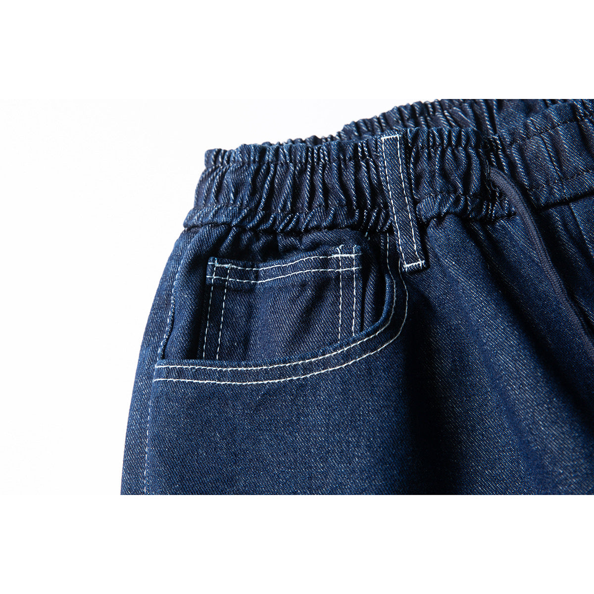 Close-up of dark indigo denim shorts showing an elastic waistband, belt loop, and back pocket with white stitching.