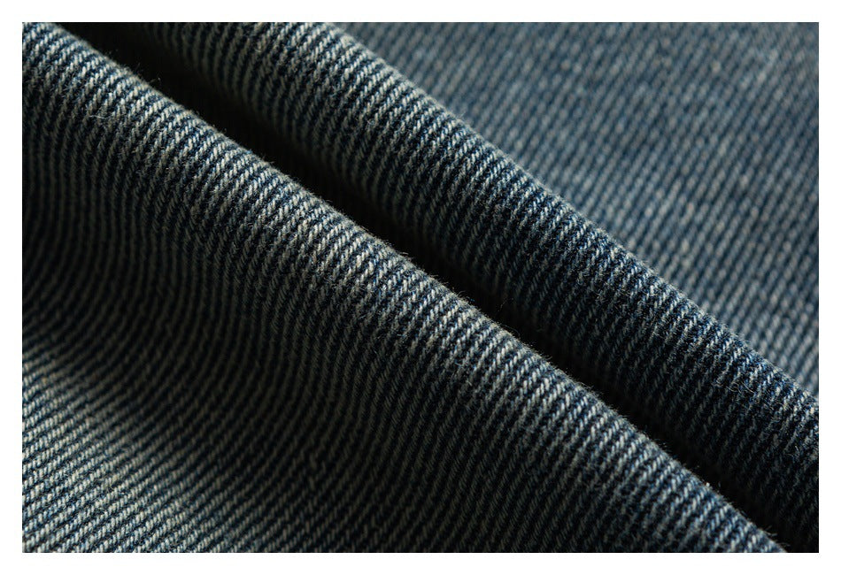 Macro close-up of dark blue denim twill showing its diagonal weave and folded edge.