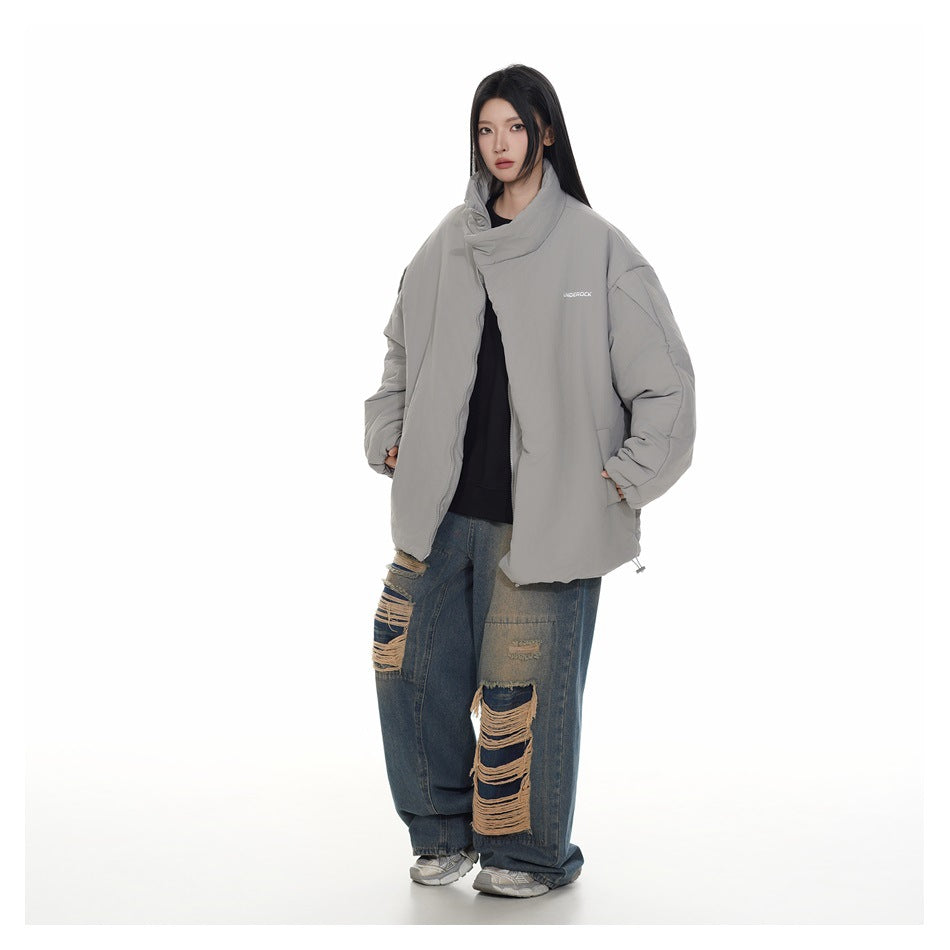 Model wearing an oversized light gray padded jacket with a tall folded collar and front zipper, paired with distressed jeans.