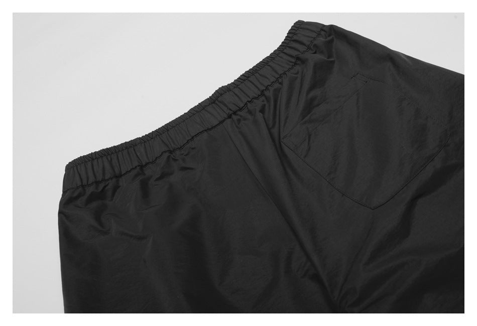 Close-up of black shorts with an elastic waistband and a rear patch pocket.