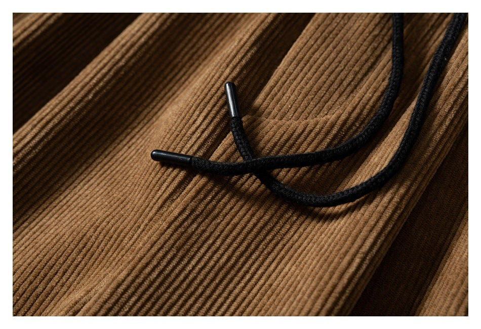 Close-up of black braided drawstrings and tips against the brown corduroy fabric.