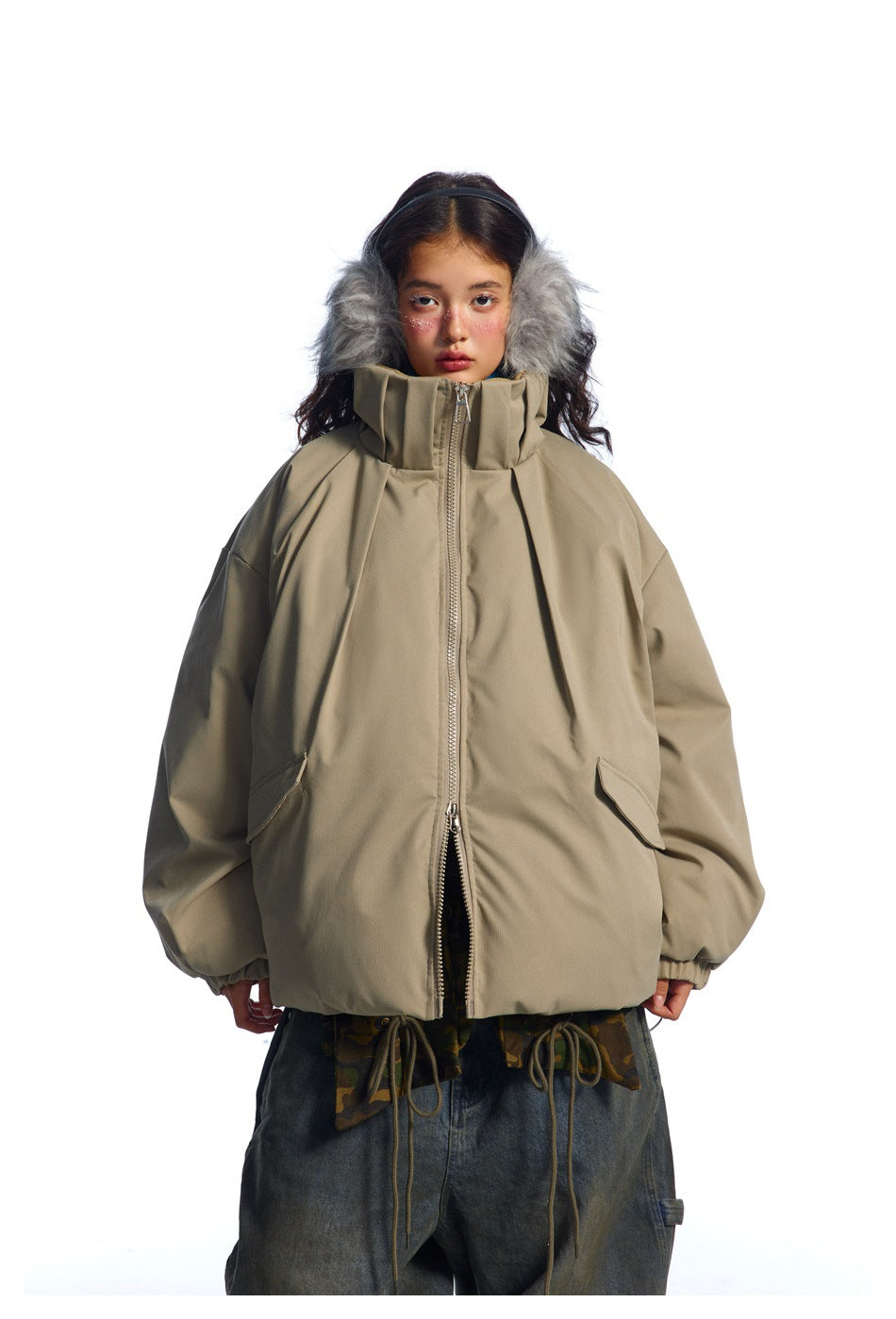 Front view of a model in an oversized taupe jacket with a high collar, gray fur-trimmed hood, and large pockets.
