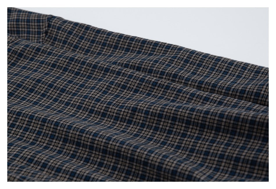Close view of dark blue, beige, and black plaid fabric with a stitched seam.