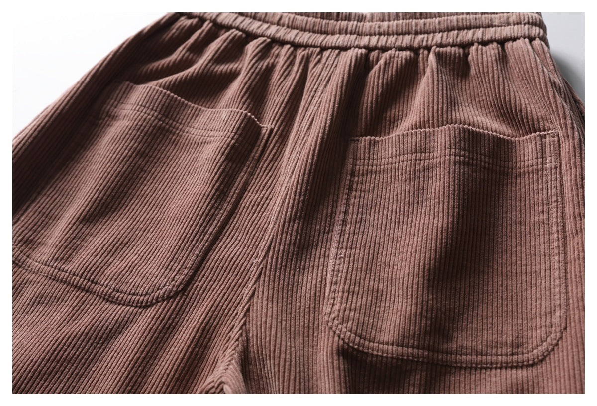 Close-up of dusty mauve-brown ribbed trousers showing a gathered waistband and two patch pockets.