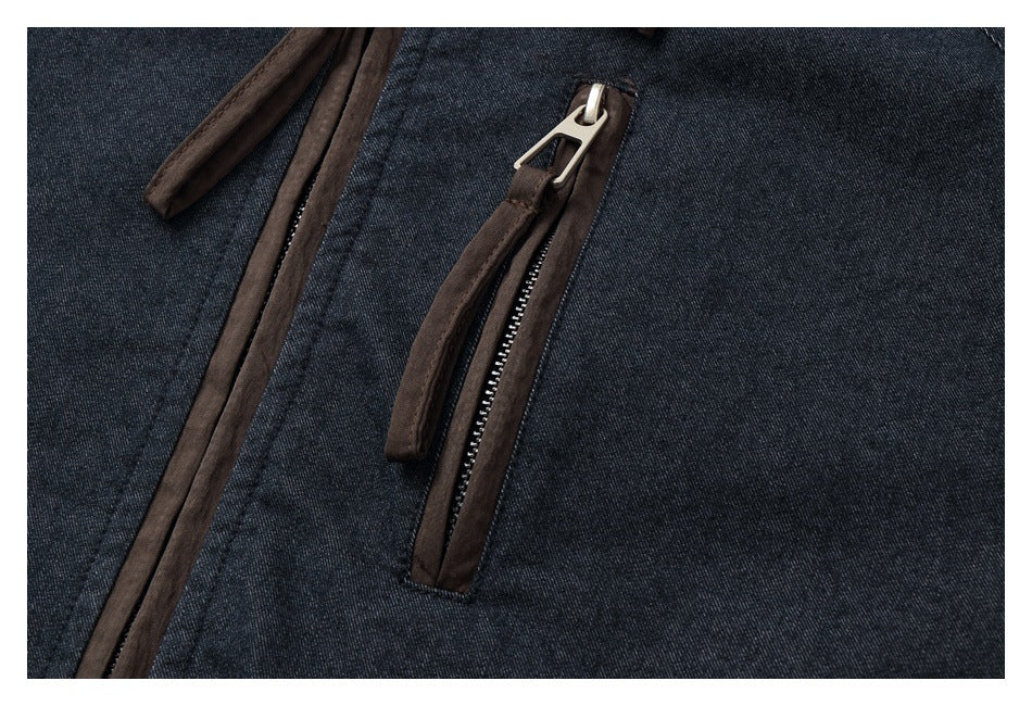 Close-up of a brown-trimmed zip pocket on dark indigo jacket fabric.