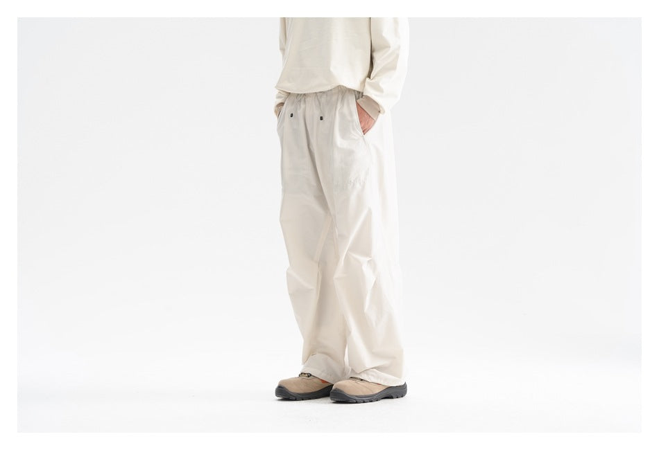 Front three-quarter view of a model wearing loose cream pants with an elastic waist and a cream top.