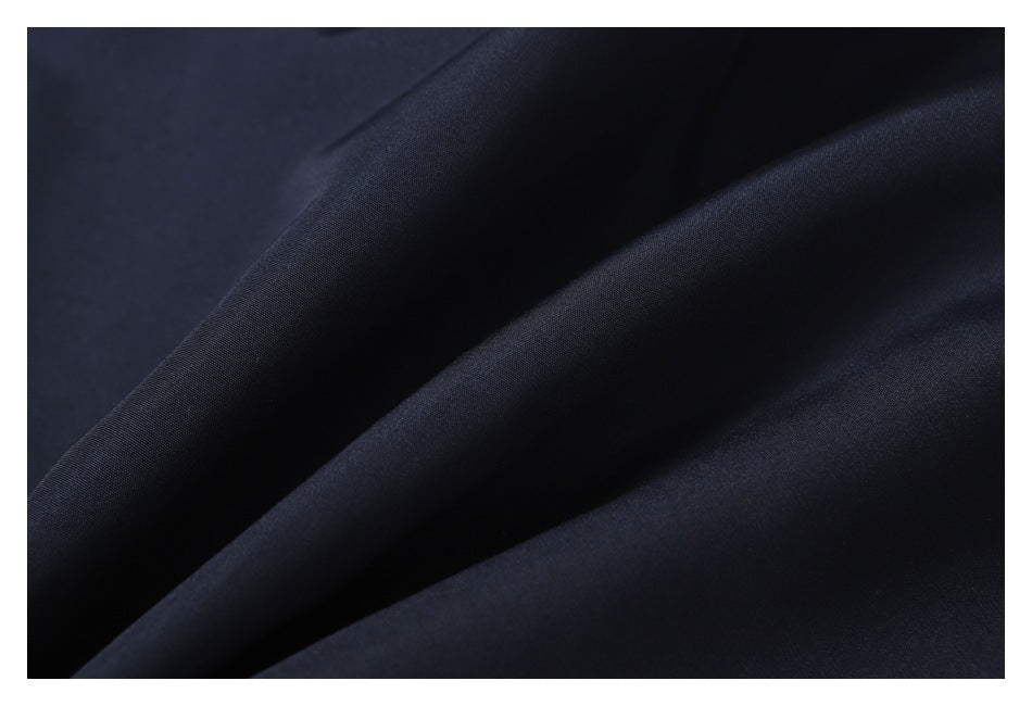 Close-up of dark navy jacket fabric folded into soft diagonal ridges.