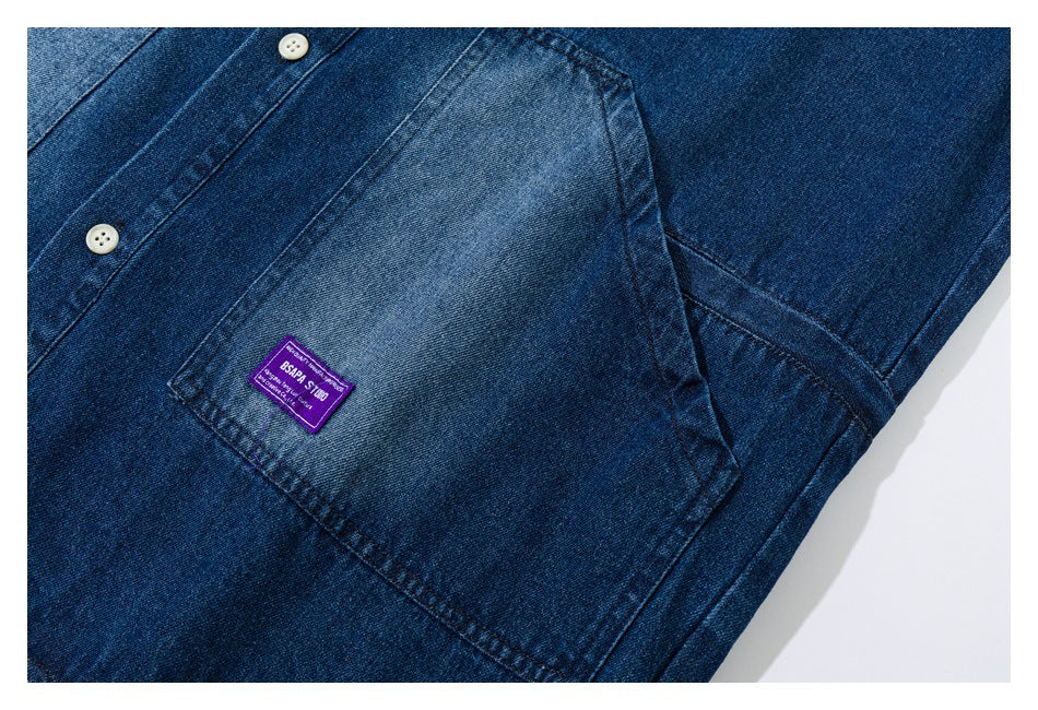 Close-up of a faded patch pocket and purple label on a blue denim shirt.