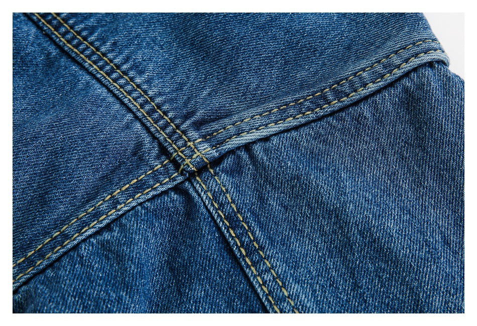 Close-up of intersecting seams on blue denim with contrasting tan topstitching.