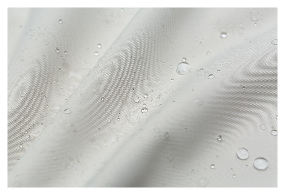 Close-up of off-white woven fabric with water droplets beading on its surface.