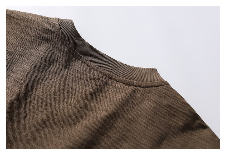 Close-up of a brown knit garment showing its ribbed crew neckline and shoulder seam.