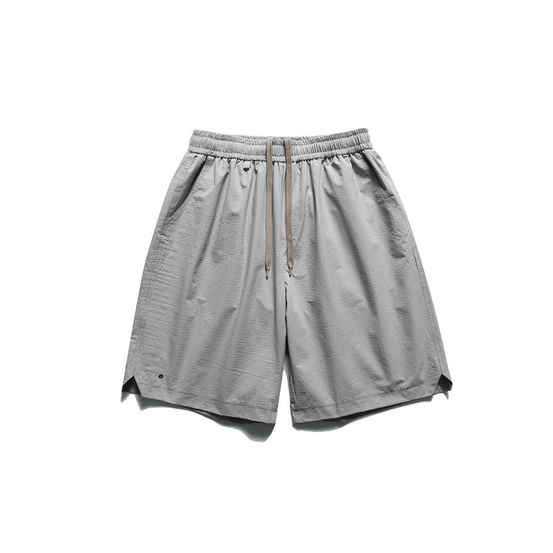 Gray knee-length shorts with elastic drawstring waist, side pockets and curved notched hem, flat lay front view