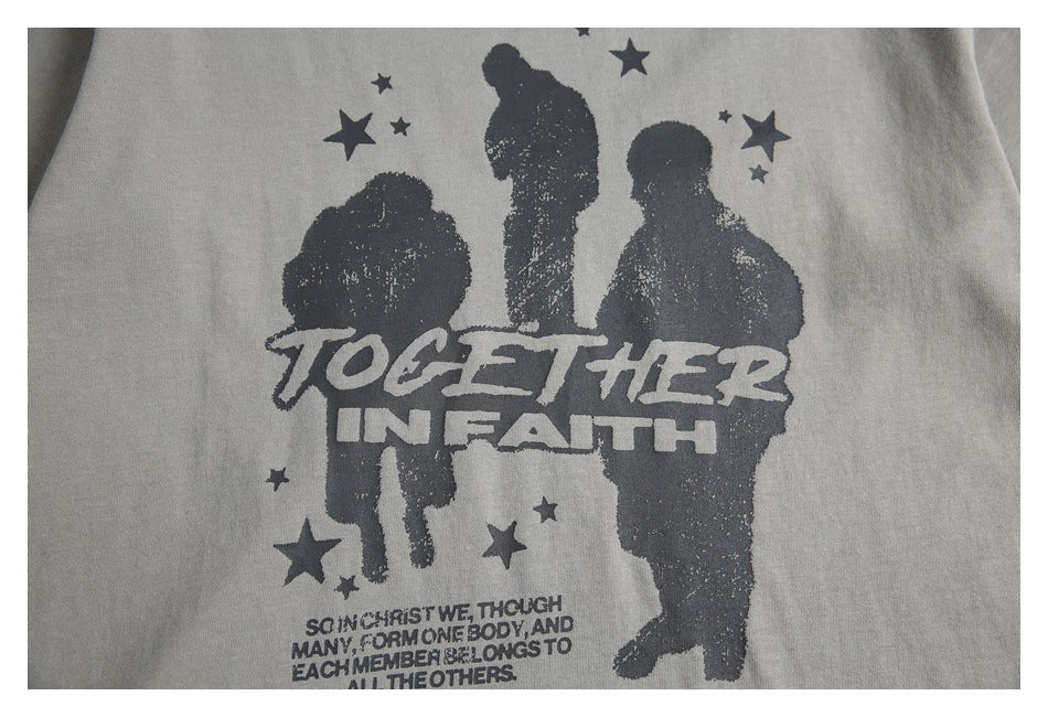 Close-up of a gray T-shirt with a dark graphic of three figures, stars and the words “Together in Faith.”