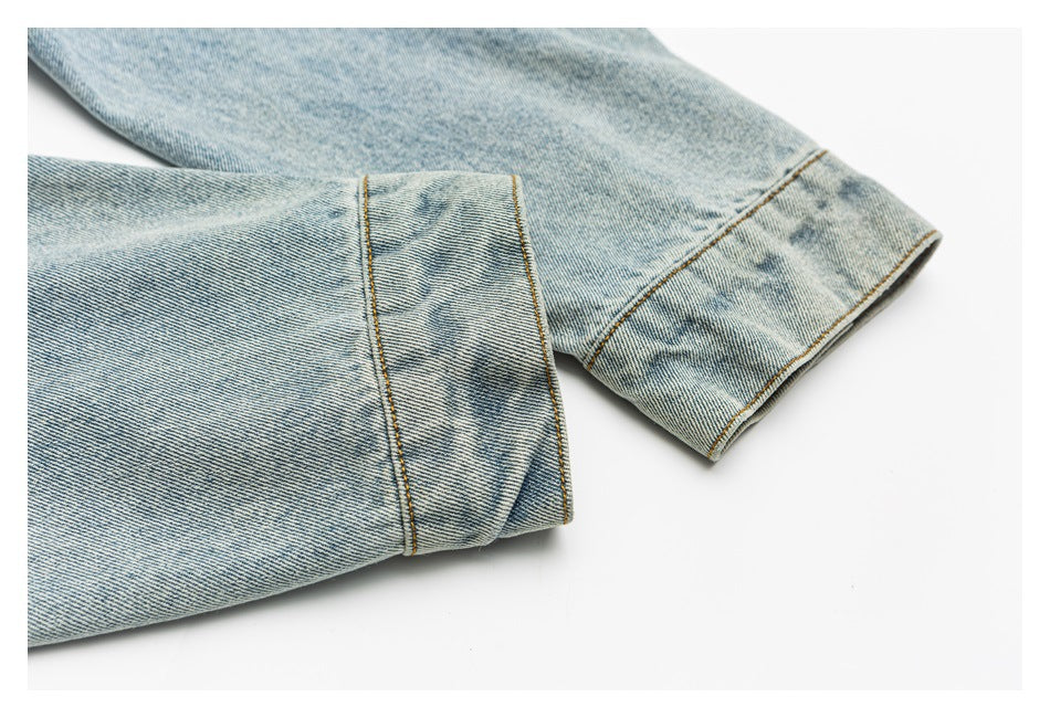 Close-up of light-wash denim jacket sleeves and folded cuffs with contrast stitching.