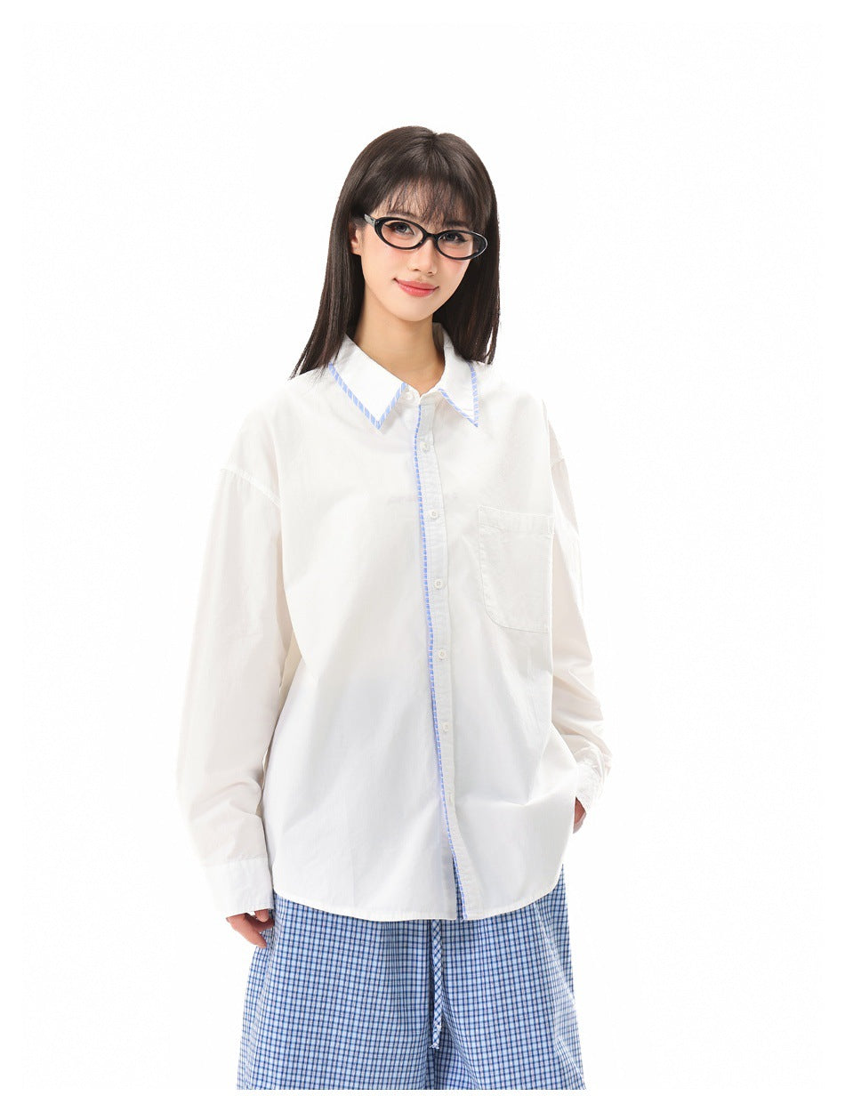Model wearing a white button-front shirt with blue striped collar and placket, paired with blue checked wide-leg trousers.