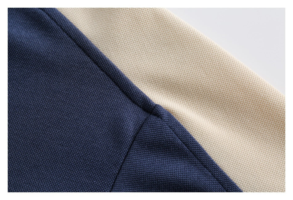 Close-up of a navy polo shoulder seam against a cream textured panel.