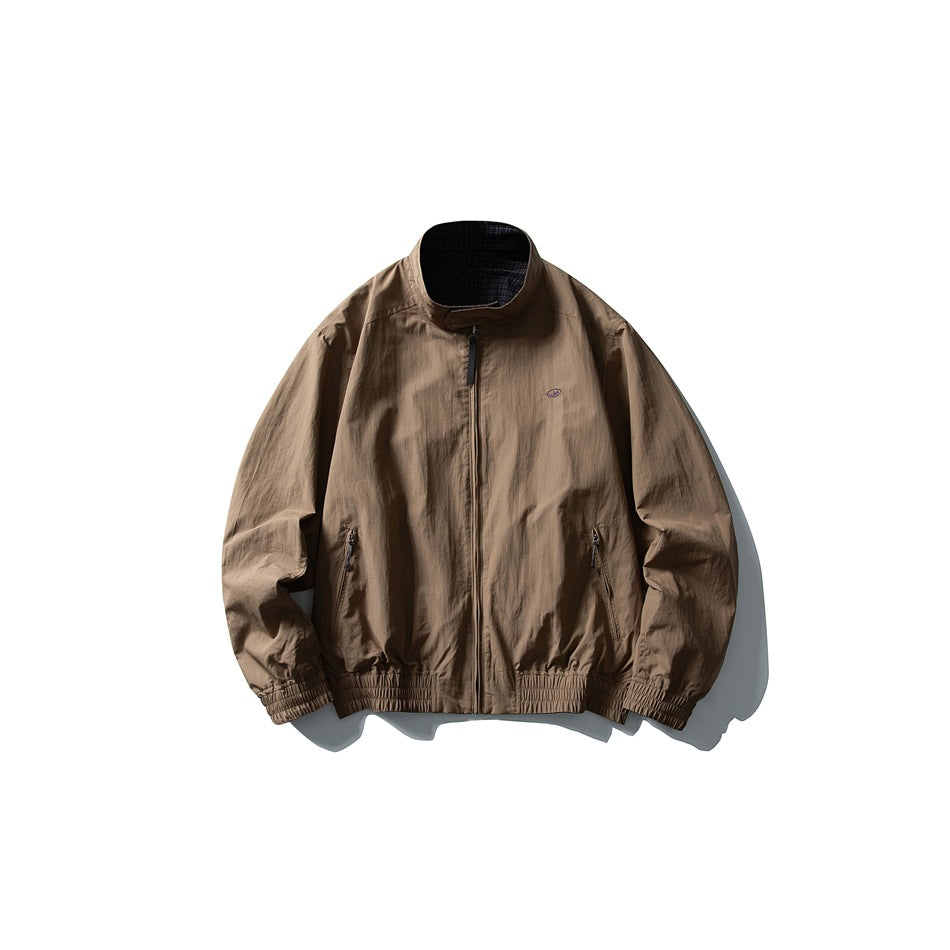 Taupe zip-front jacket with a stand collar, two zip pockets, elastic cuffs and hem, and a small chest emblem.