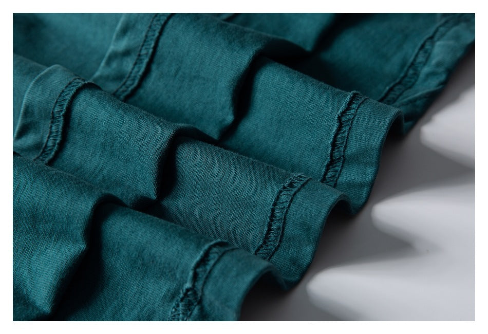 Close-up of teal fabric showing folded edges and visible overlock stitching.