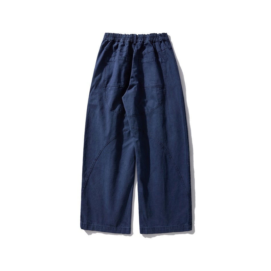 Back view of washed blue wide-leg pants with elastic waistband section, back pockets and curved seams