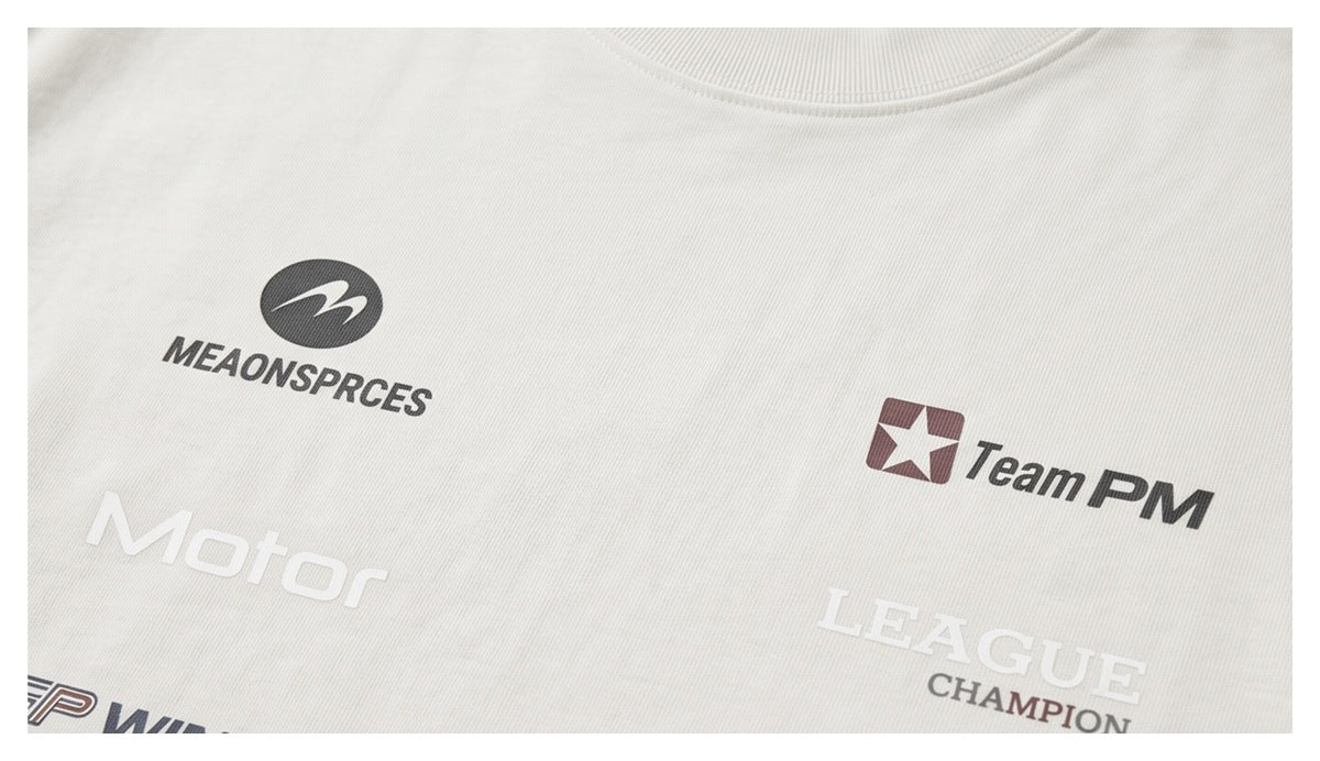 Close-up of white fabric printed with several racing-style logos and English lettering.