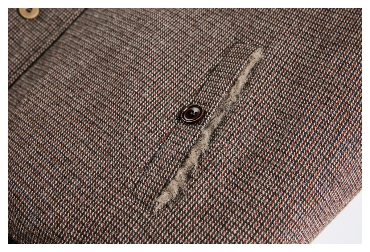 Close-up of a narrow pocket opening and button on the coat's brown patterned fabric.