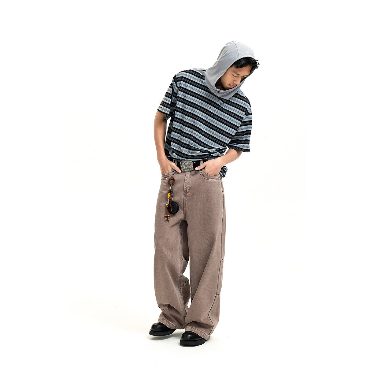 A man models a black and gray striped short-sleeve hooded shirt with loose taupe pants.