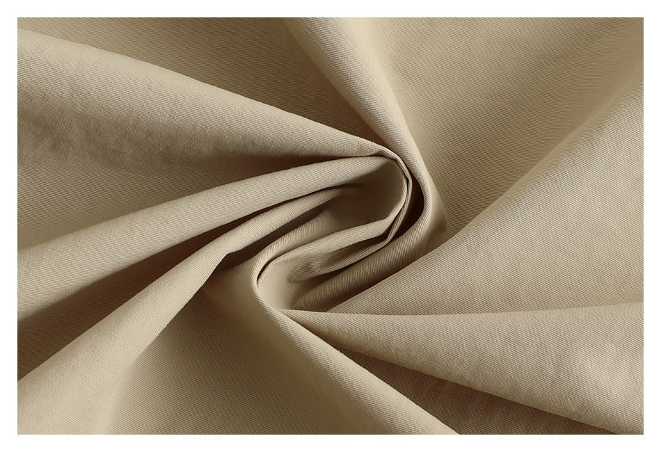 Close-up of beige fabric draped into folds, showing its fine surface texture.