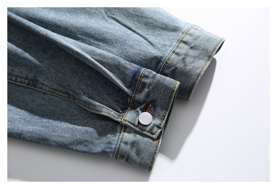 Close-up of a blue denim jacket sleeve and buttoned cuff.