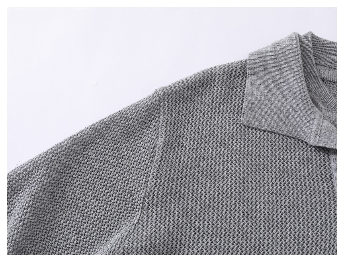 Close-up of a gray textured knit sweater showing its ribbed polo collar and upper body.