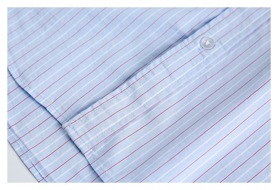 Close-up of a light blue striped shirt cuff with a white button and visible stitching.