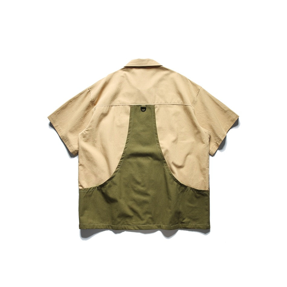Back of a khaki short-sleeve shirt with a curved olive green panel and a small D-ring at the upper back, flat lay