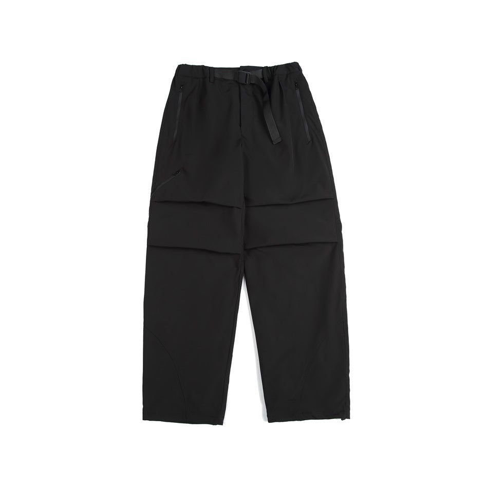 Black wide-leg pants with matching belt, zippered pockets, knee pleats and curved lower-leg seams, flat lay