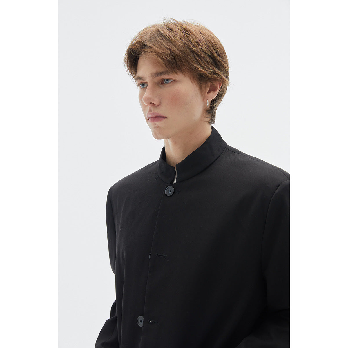 Close view of a model wearing a black stand-collar jacket with a button front.