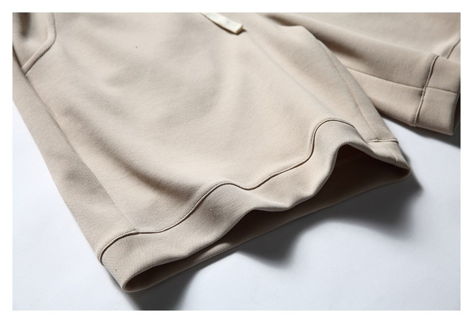 Close-up of the wide hem and stitched curved seam on beige shorts.