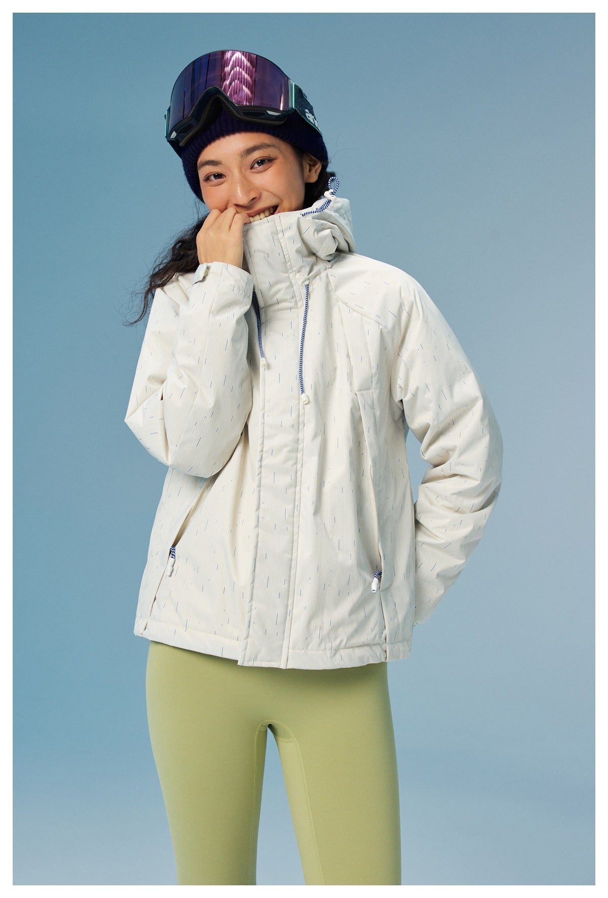 Model wearing a white hooded jacket with fine blue dash pattern, blue drawcords, and front pockets.