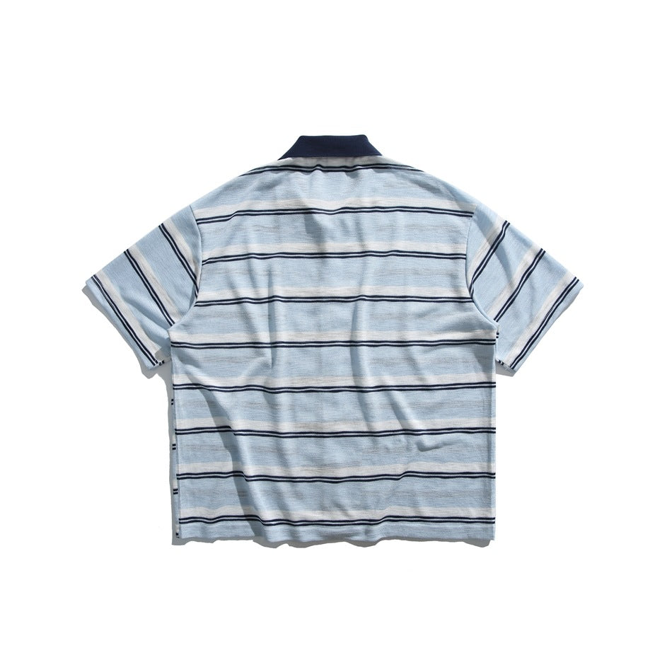 Back view of a light blue shirt with white and navy horizontal stripes and a navy collar, laid flat