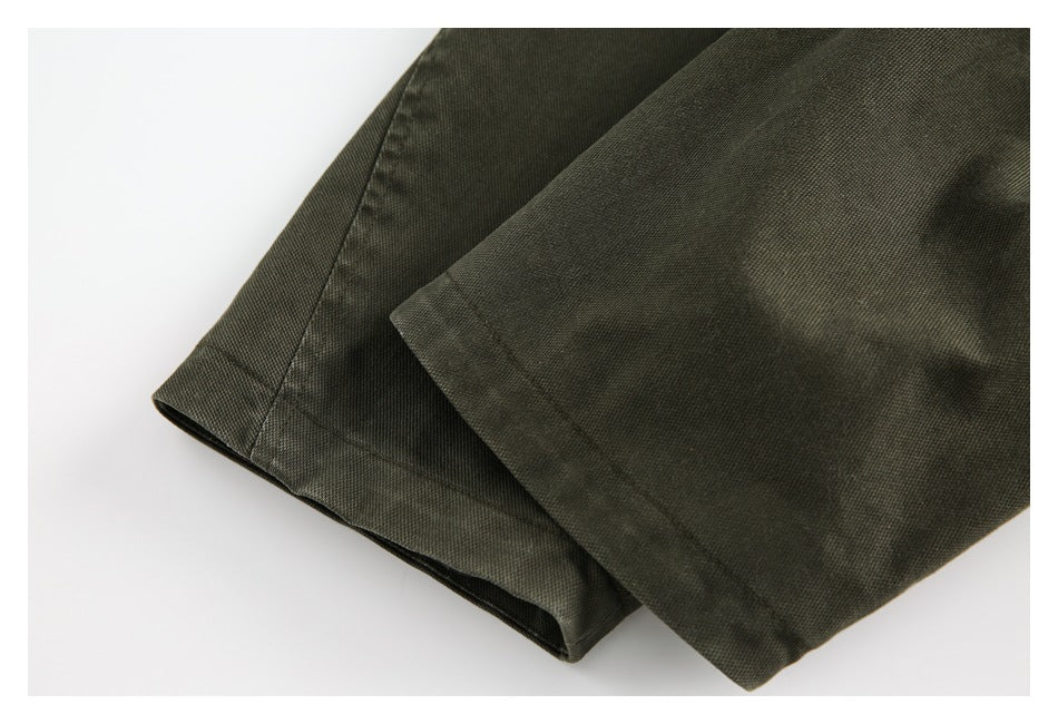 Close-up of the olive jacket's folded hem and stitched edge.