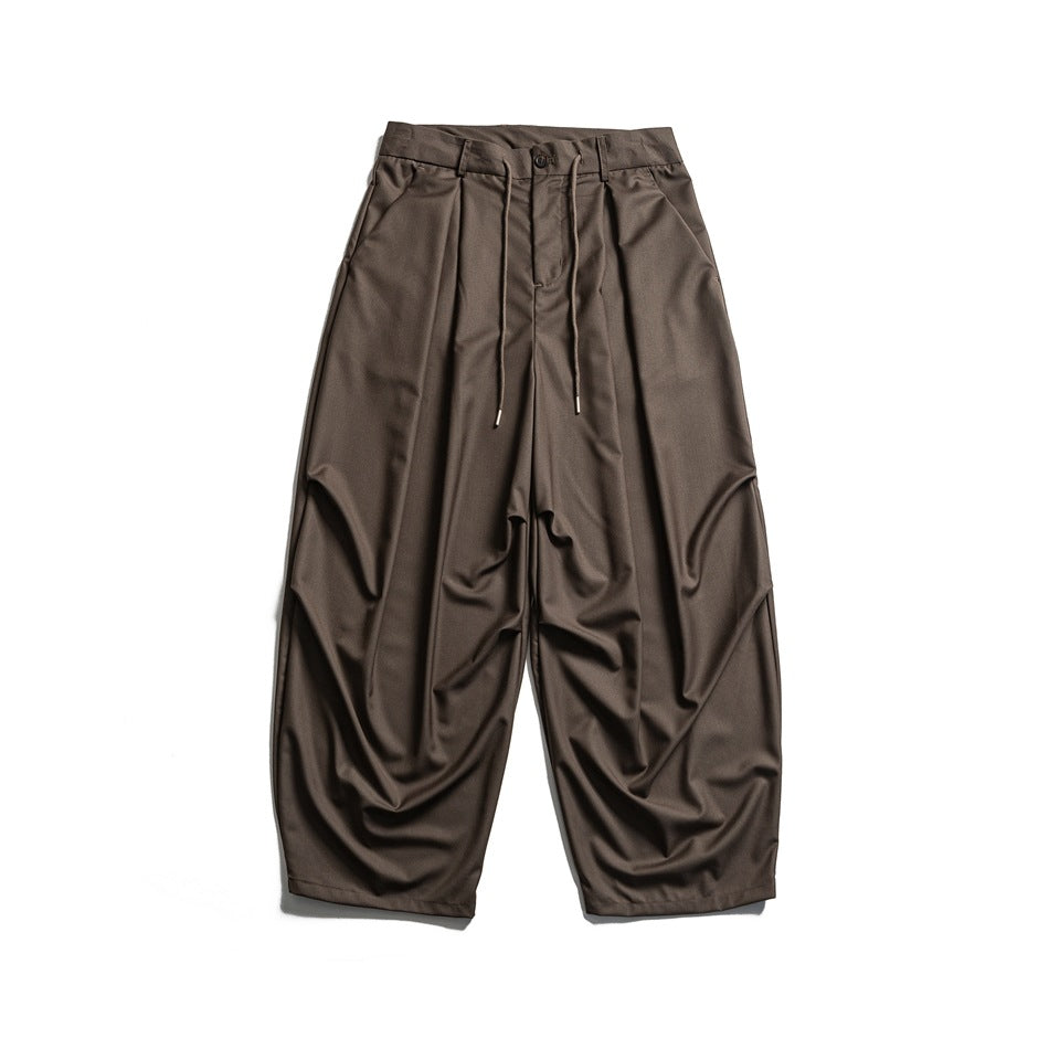 Brown wide-leg pleated trousers with drawstring waist and button front, flat lay front view