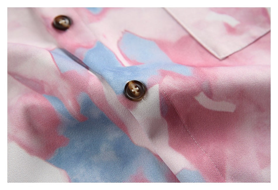 Close-up of a brown shirt button and the pink, white, and blue abstract print.